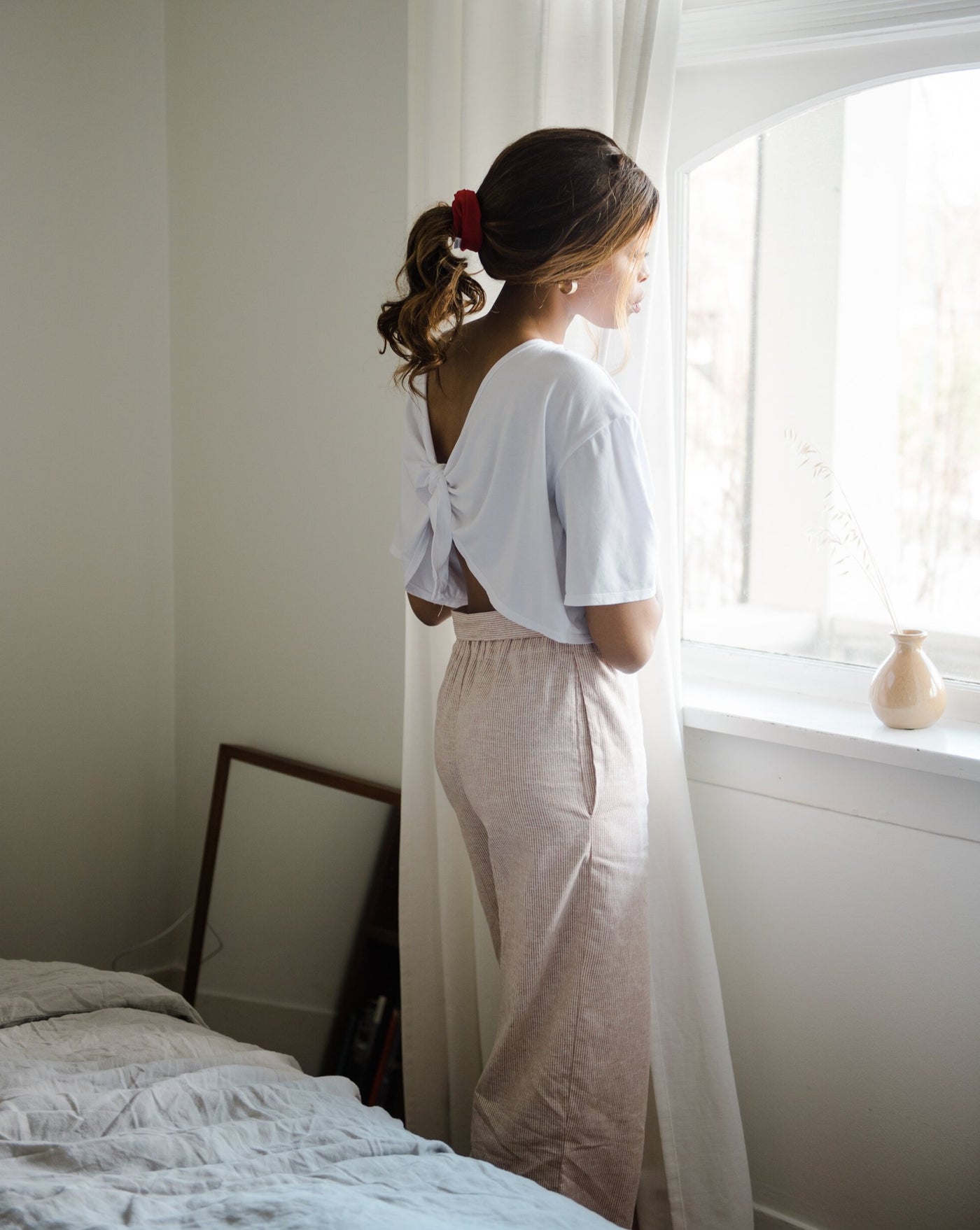 White tencel organic cotton reversible tie top worn by model standing by a window.