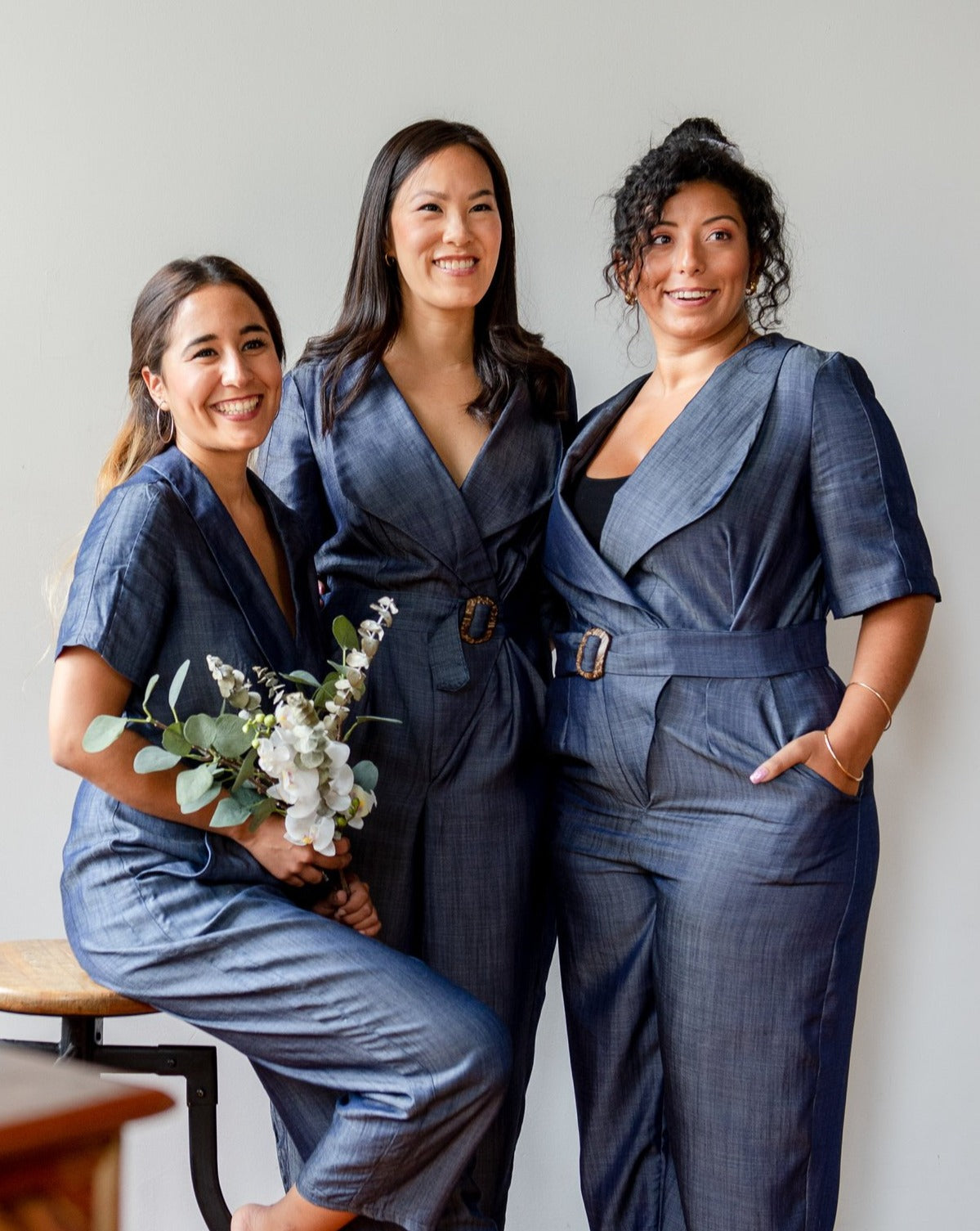 Three models weawring the blue chambray Tencel denim pantsuit with coconut shell buckle belt.