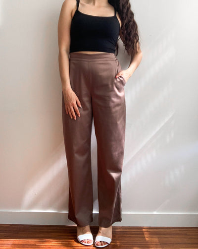 Light brown loose trousers made from organic cotton and tencel,with back elastic waistband worn with a black tank top.