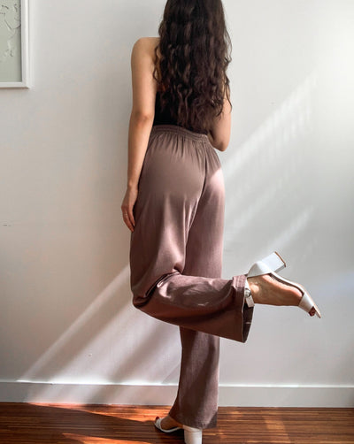 Light brown loose trousers made from organic cotton and tencel,with back elastic waistband worn with a black tank top.