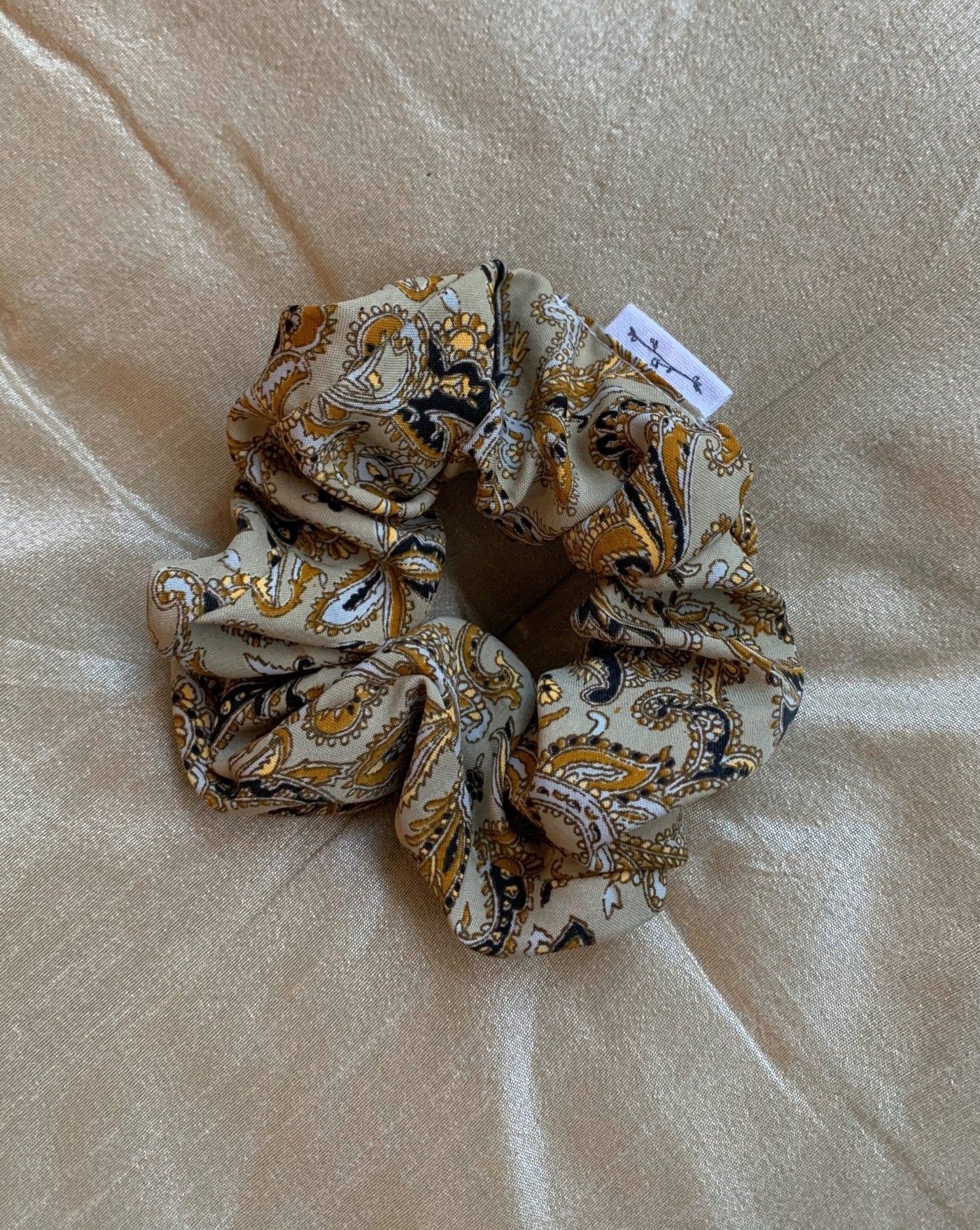 Beige, black, yellow and white paisley reclaimed silk fabric scrunchie ethically sewn in Canada.