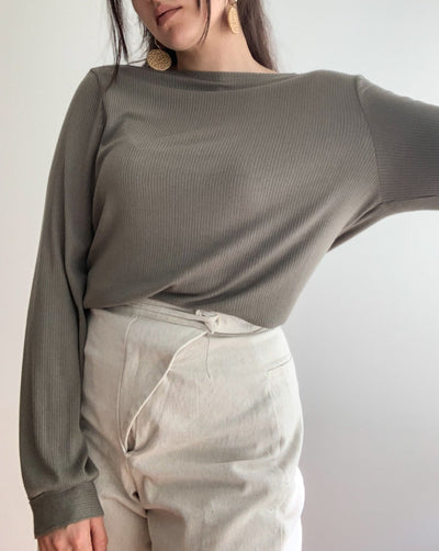 Ribbed reversible wrap top in the colour olive worn with beige pants.