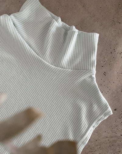 Sustainable Tencel modal ribbed sleeveless mint-coloured turtleneck worn with black trousers.