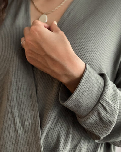Sustainable olive green ribbed tencel reversible shirt with gold necklace.