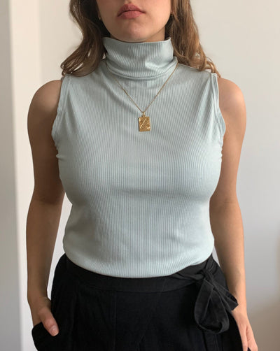Sustainable Tencel modal ribbed sleeveless mint-coloured turtleneck worn with black trousers.