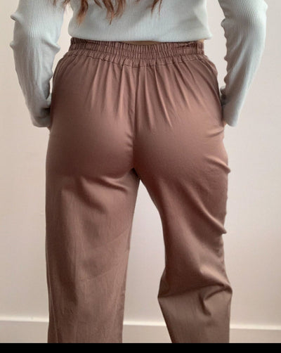 Light brown loose trousers made from organic cotton and tencel,with back elastic waistband worn with a beige turtleneck.