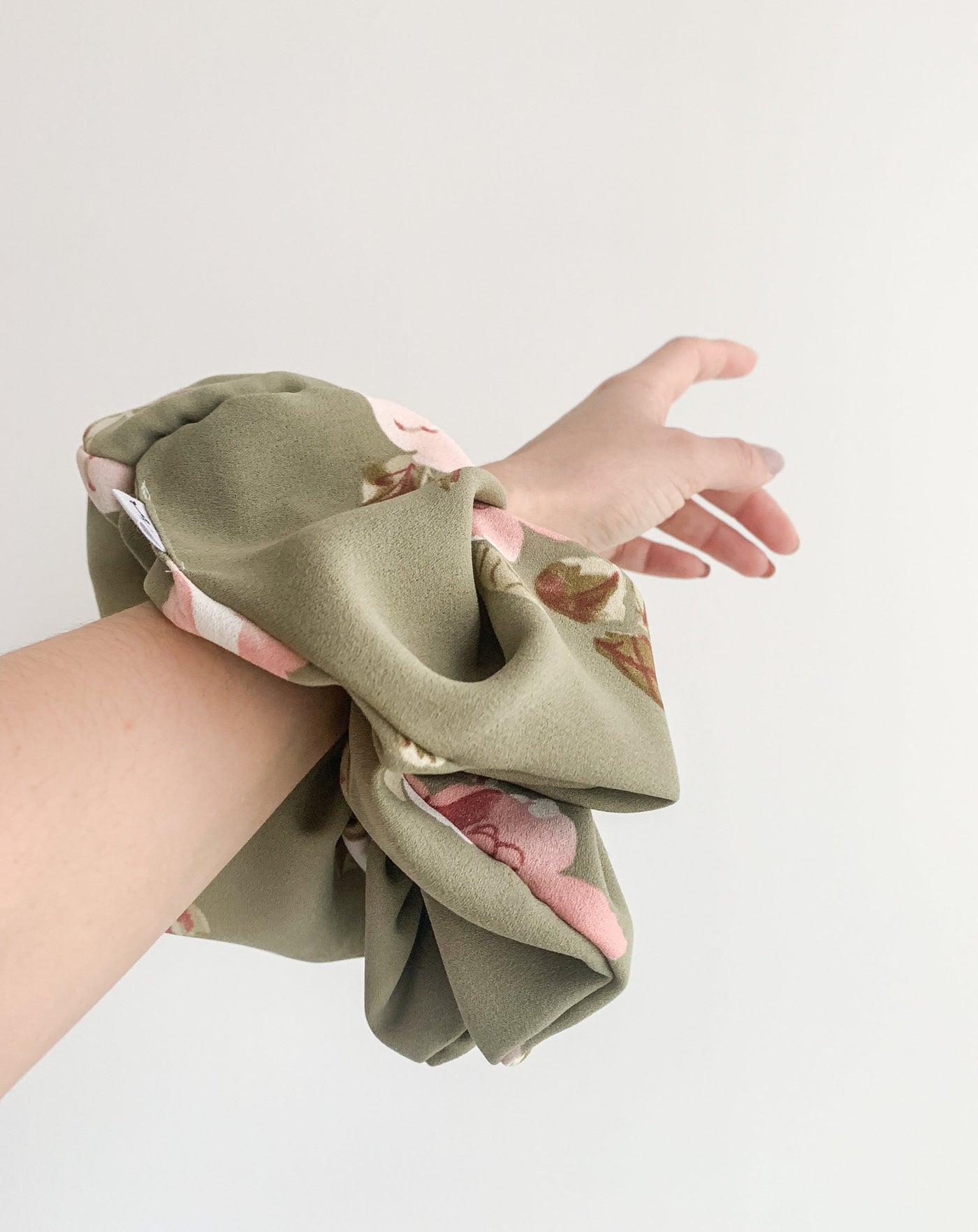 Fluffy Grande Luxe floral green scrunchie on arm.