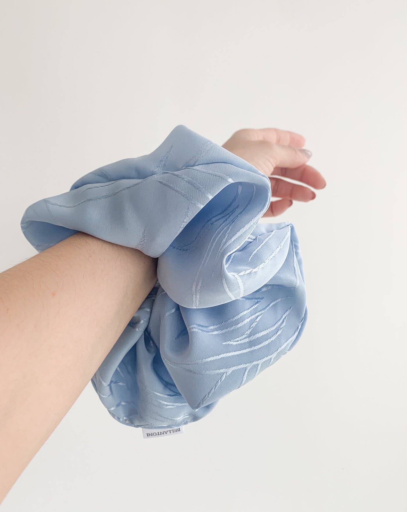 Grande Luxe frozen blue scrunchie on arm.
